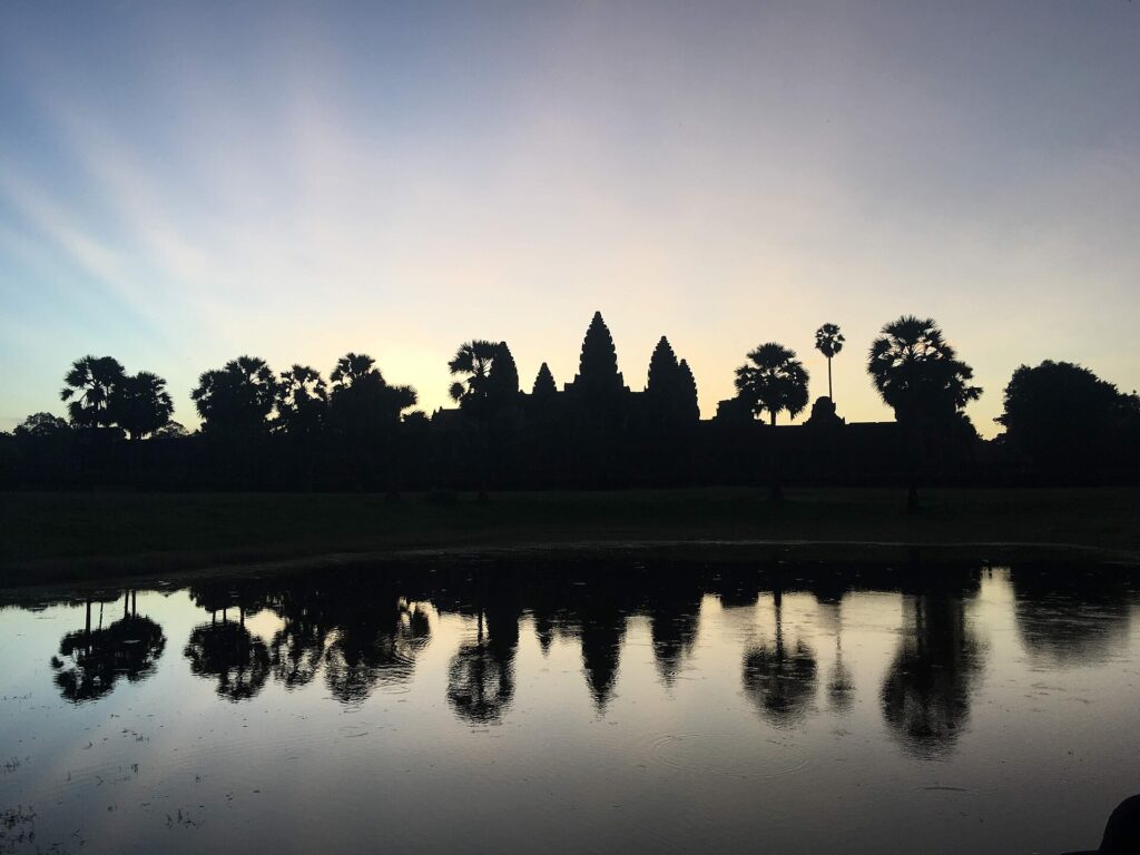 Angkor Wat at sunrise with its five towers reflected in a pond in Cambodia