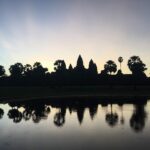 Angkor Wat at sunrise with its five towers reflected in a pond in Cambodia
